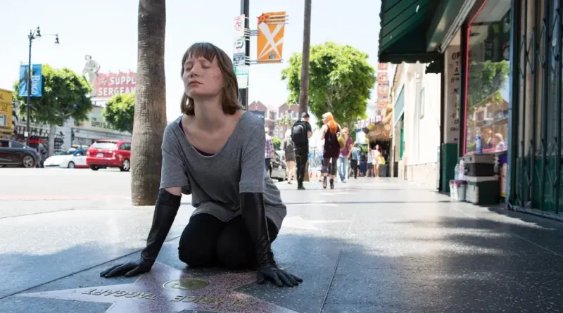 Agatha kneeling down and touching Clarice's star on the Hollywood Walk of Fame in "Maps to the Stars".